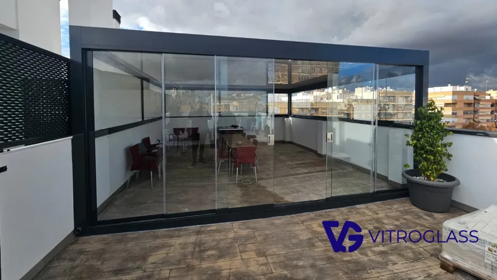 Cortinas de cristal instaladas en terraza con pérgola fija para cerramiento exterior
